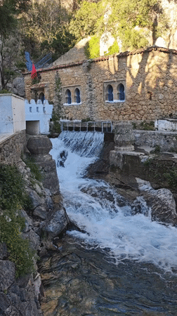 Waterfall flows past traditional blue-shuttered building in Chefchaouen