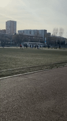 Football players gather on artificial turf during daytime match
