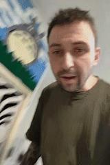 Man displays zebra-striped woman's face rug creation indoors