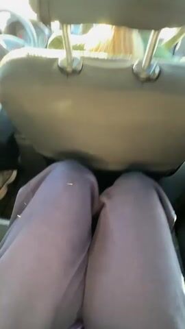 The video shows the interior of a car from the passenger seat. A man is driving, seen from the back. The car is moving on a road. The dashboard, steering wheel, and rearview mirror are visible. There is a small ornament hanging from the rearview mirror. A passenger is in the front seat, partially visible. Music is playing in the background.