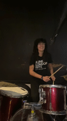 Woman plays drums amid musical equipment in Buenos Aires venue