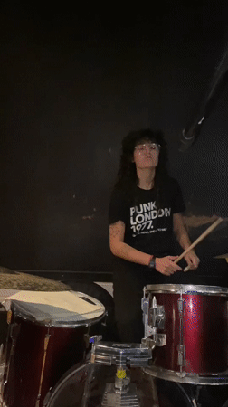 Woman plays drums amid musical equipment in Buenos Aires venue