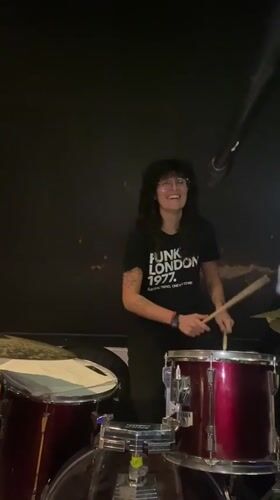 Woman plays drums amid musical equipment in Buenos Aires venue