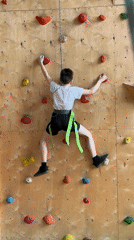 Young boy climbs indoor rock wall at recreational facility