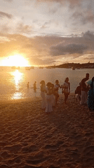 Beach sunset gathering features dancing, music, pelicans on June 11