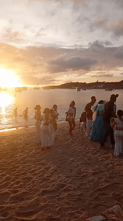 Beach sunset gathering features dancing, music, pelicans on June 11
