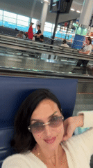 Woman takes selfie at airport terminal near moving walkway