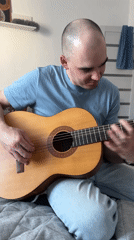 Man plays guitar for smiling woman in Yekaterinburg bedroom