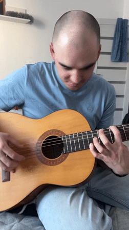 Man plays guitar for smiling woman in Yekaterinburg bedroom