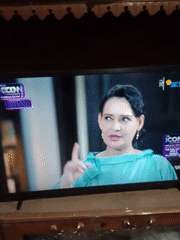 Television broadcast captured showing woman in light blue top