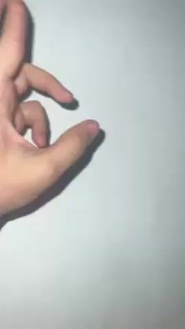 The video shows a hand demonstrating flexibility of the fingers. At first the ring and middle fingers are curled over each other, then the fingers are splayed apart. The hand has medium skin tone and short fingernails. The background is a flat off-white surface. The hand casts a shadow.