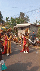 Traditional procession with red and black dress moves through Sumurmati streets