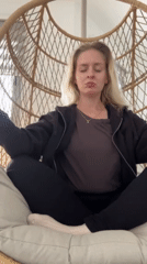 Woman practices meditation in rattan chair, self-care moment captured