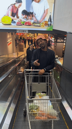 Shopper navigates supermarket escalator with full cart in Beijing