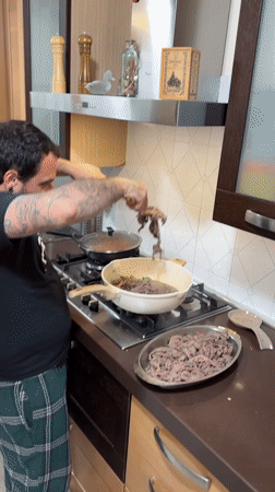 Domestic evening scene: man cooking, dog playing in Italian home