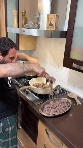 Domestic evening scene: man cooking, dog playing in Italian home