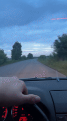 Car travels rural road under overcast morning sky