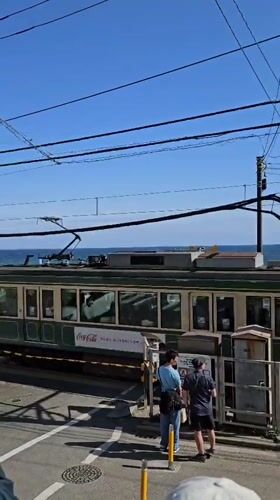 Morning tram crosses street in coastal Kamakura, Japan