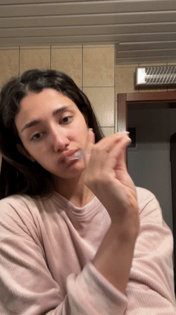 Woman brushes teeth in Sutomore bathroom morning routine