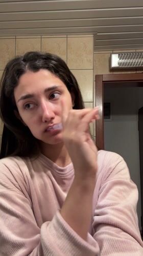 Woman brushes teeth in Sutomore bathroom morning routine