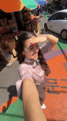 Woman films selfie video in sunny Seoul market street