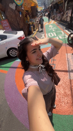 Woman films selfie video in sunny Seoul market street