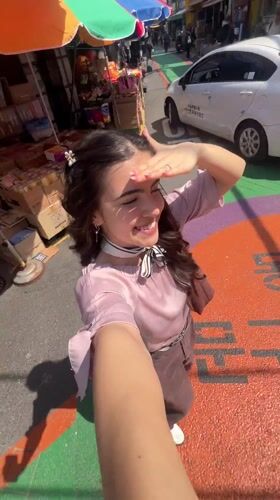 Woman films selfie video in sunny Seoul market street