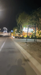 Moving vehicle captures Vietnam coffee shop on dimly lit street