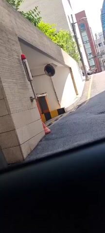 The video shows a diamond-plated steel surface, likely a road plate or cover, from a low angle. It is situated in an urban setting, with a road and building visible in the background. There is an orange stripe on the edge of the steel plate. The overall impression is of a temporary construction or maintenance setup on a city street.