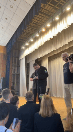 Book signing on a Kyiv stage, Ukrainian flag patches on uniform