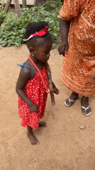 Girl in red dress stands with woman in Akwanga