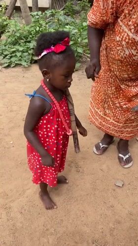 Girl in red dress stands with woman in Akwanga