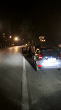 Three people gather near parked cars in Gabrovo