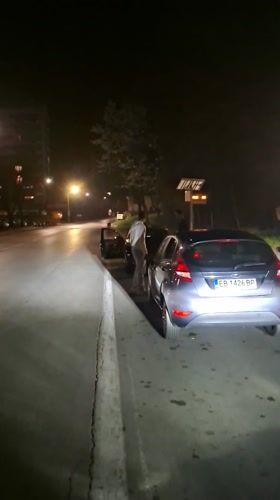 Three people gather near parked cars in Gabrovo