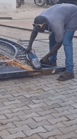 Man operates angle grinder outdoors in Gwagwalada, Nigeria