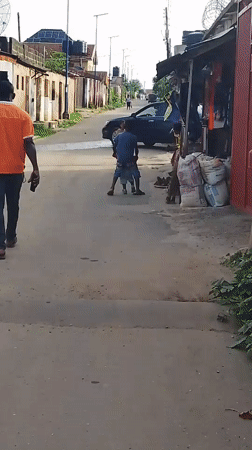 Person in orange shirt walks street in Ohokobe Ndume