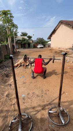 Man conducts outdoor weightlifting workout in rural Nigeria