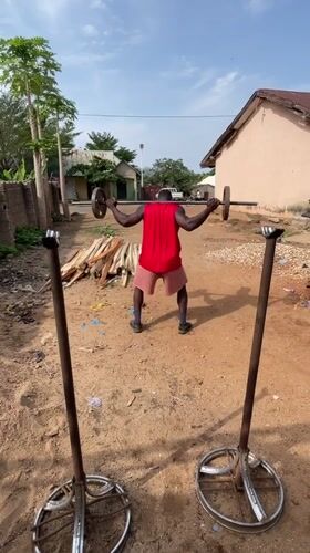 Man conducts outdoor weightlifting workout in rural Nigeria
