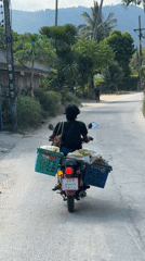 Motorcyclist travels narrow road in Baan Lamai, Thailand