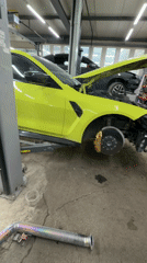Green BMW undergoes brake maintenance at repair shop