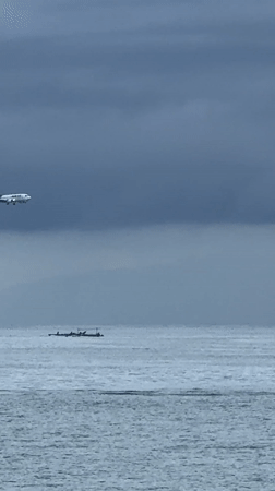 Aircraft descends over Indonesian waters as fishermen work nearby