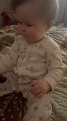 Baby plays with remote control on bed in Chaykovsky