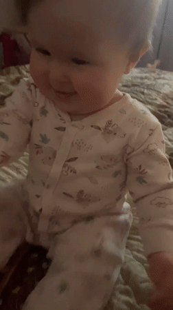 Baby plays with remote control on bed in Chaykovsky