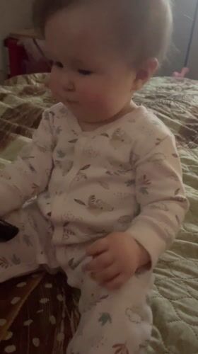 Baby plays with remote control on bed in Chaykovsky