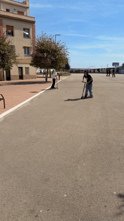 Scooter rider performs jump stunt in Spanish urban square