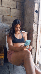 Woman checks turquoise phone in brick-walled area