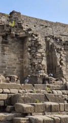 Tourist documents ancient stone ruins and fort structures in Kaswara